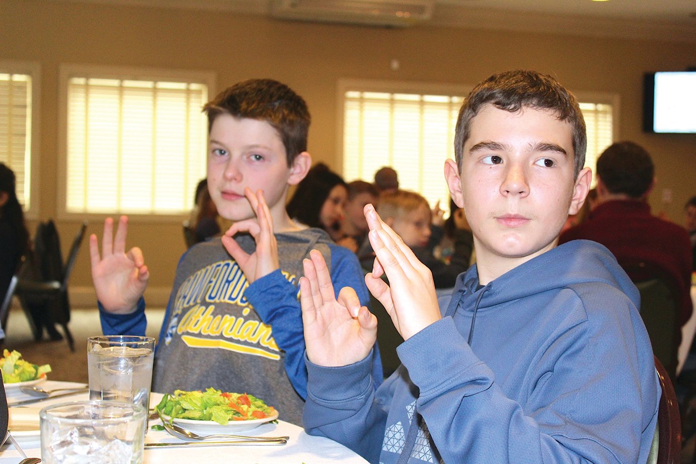Middle schoolers Andrew Turner, left and Dylon Wolcott learn to use their hands when remembering which side of the plate the bread and drink are placed. The pair attended an etiquette class at the Crawfordsville Country Club alonside more than 90 other Crawfordsville sixth graders on Monday.